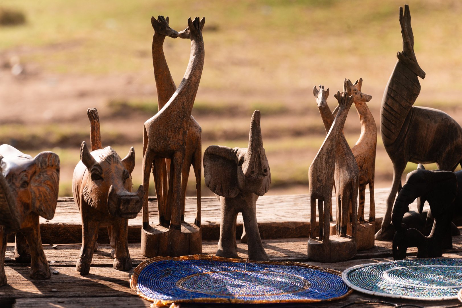 Collection of handcrafted wooden animal figurines beautifully arranged on a wooden surface outdoors.